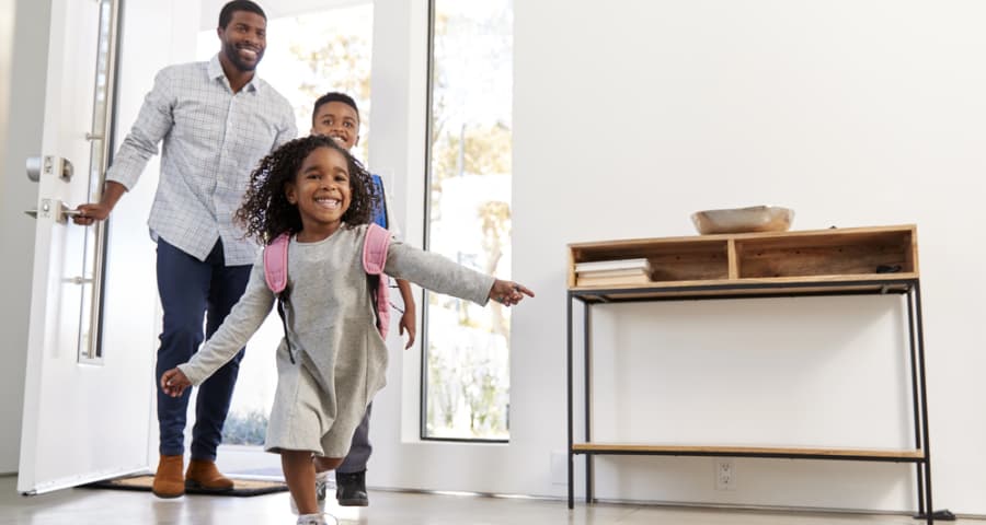 Father and children coming through the front door of their home